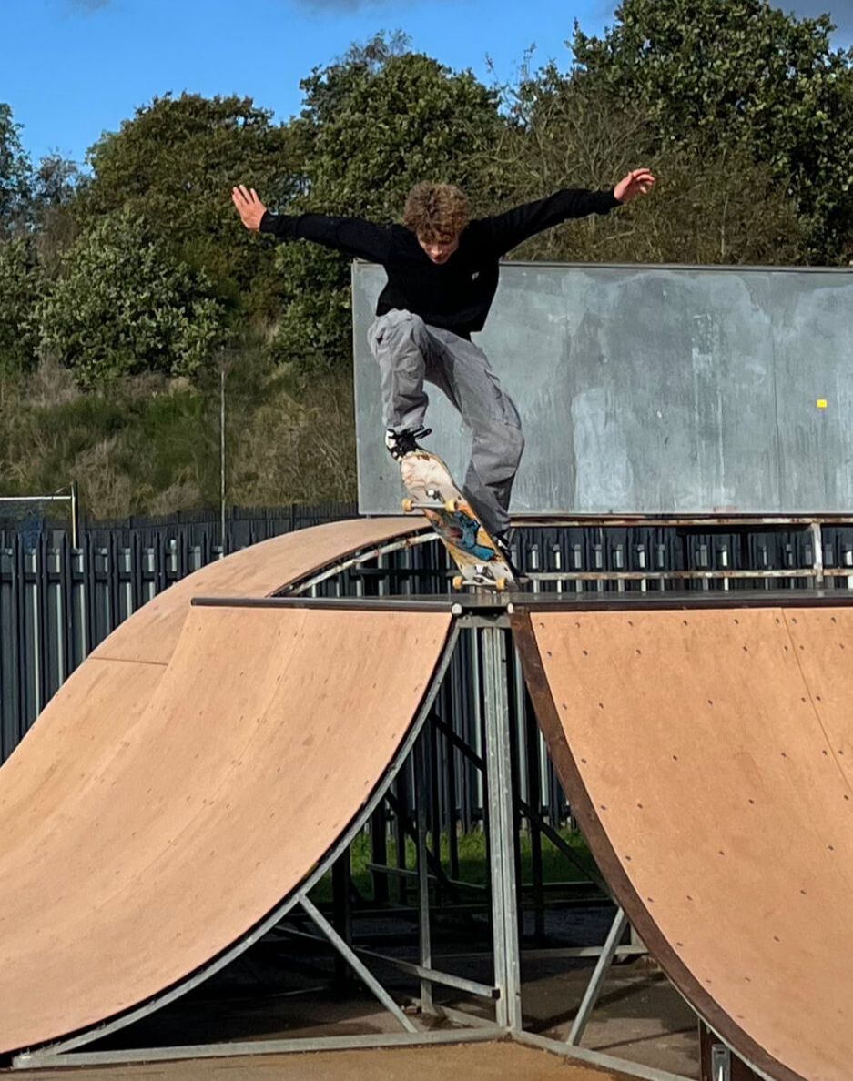Image showing a Young person jumping while on a skate board going down a ramp at Greatness Skate Park during the re-opening event. 